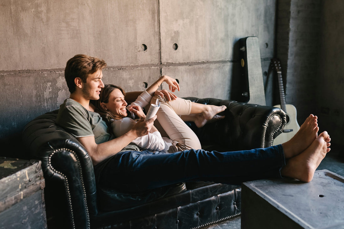 Happy couple relaxing together on a black leather couch in a cozy living room setting