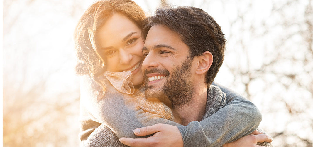 Happy smiling couple embracing outdoors in natural sunlight, illustrating joy and personal pleasure.
