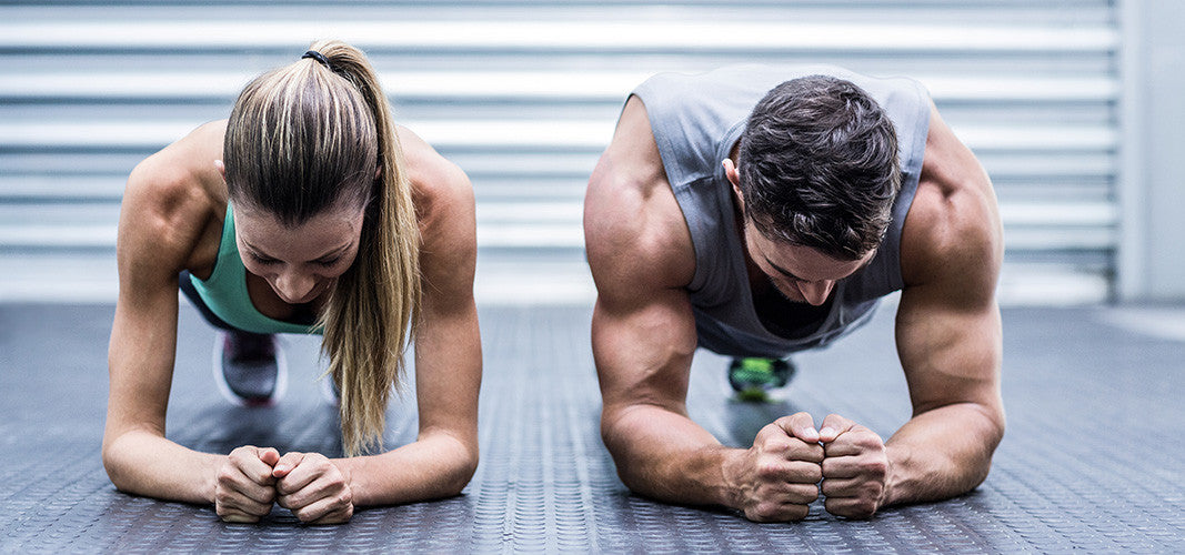 Man and woman performing plank exercise targeting core muscles in gym setting