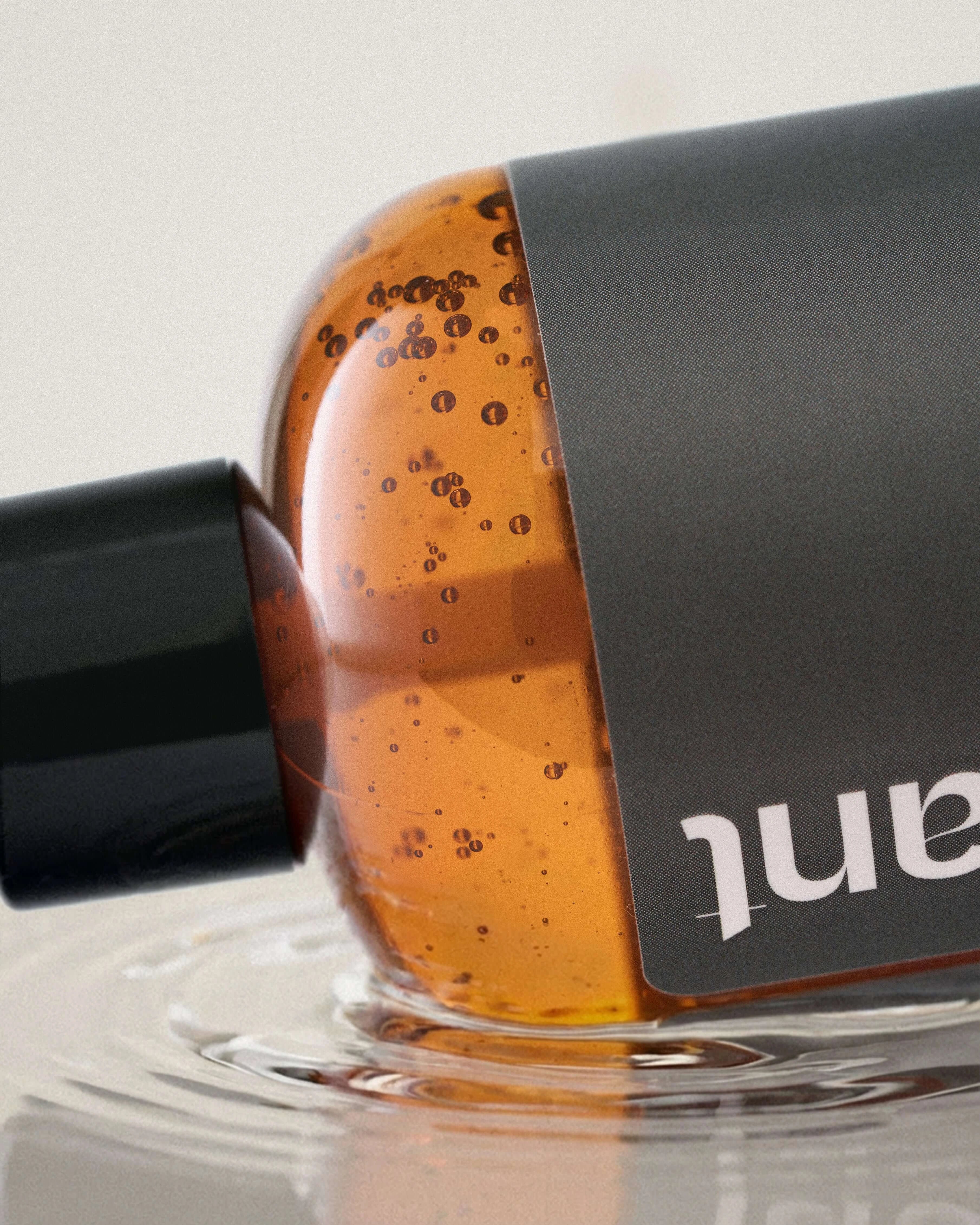 Penchant water based personal lubricant bottle close-up, partially submerged in water with bubbles, lifestyle product photo